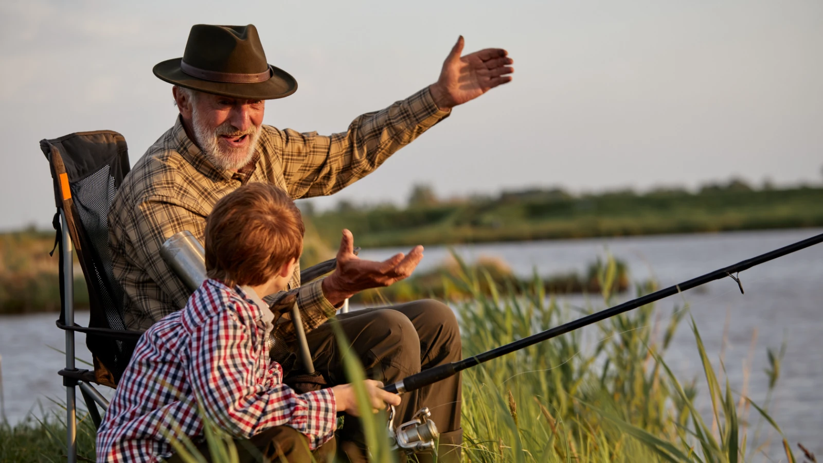 senior man enjoying outdoors and fishing with grandson