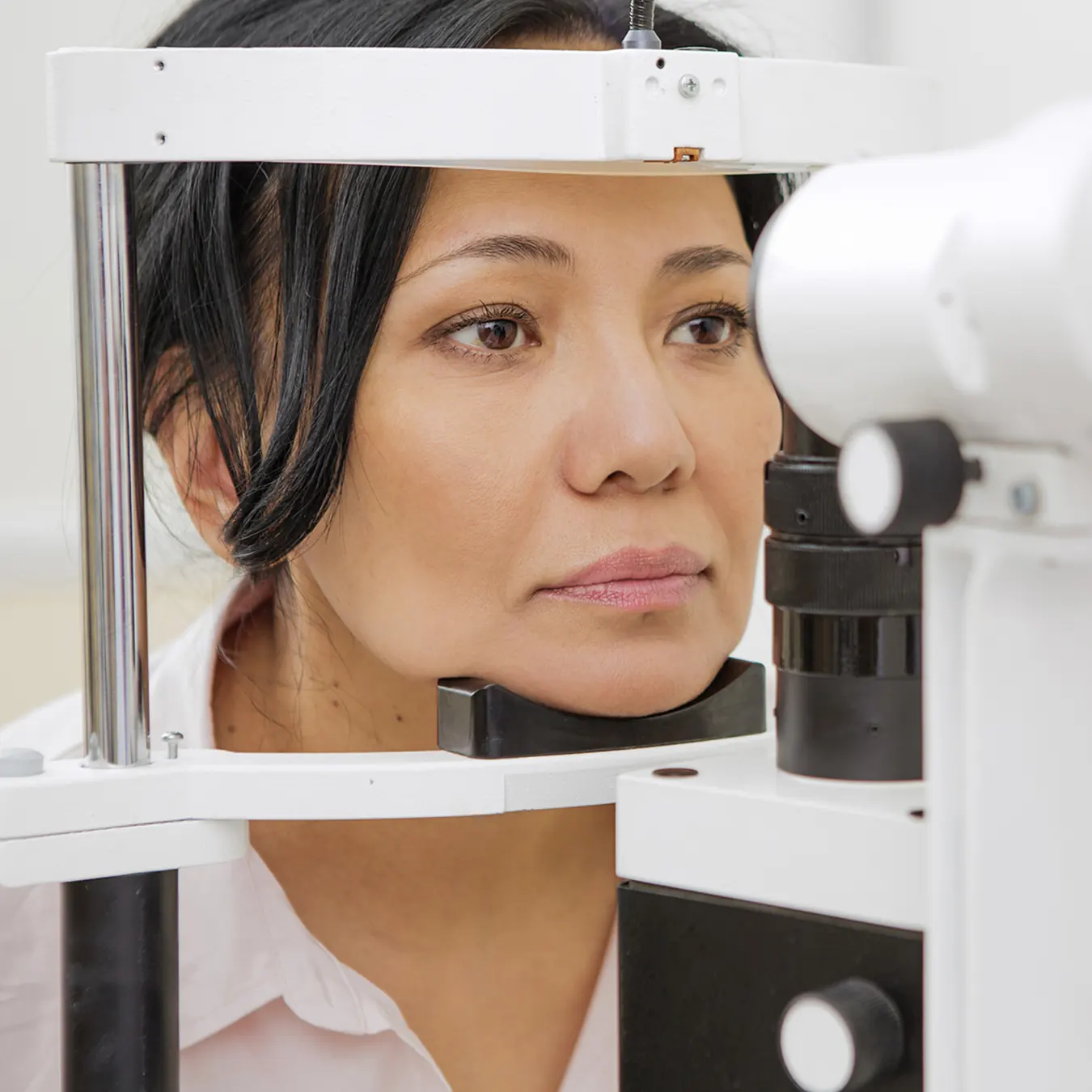 40's woman having eyes examined with slit lamp