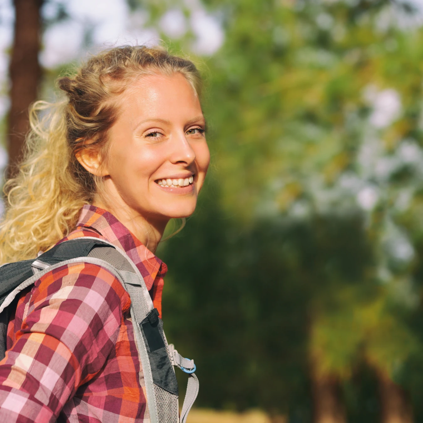 young woman hiking on a trail, smiling